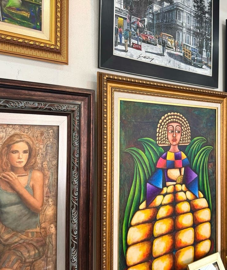 Pared de la galería BellArt con obras originales enmarcadas, entre ellas un retrato en moldura dorada